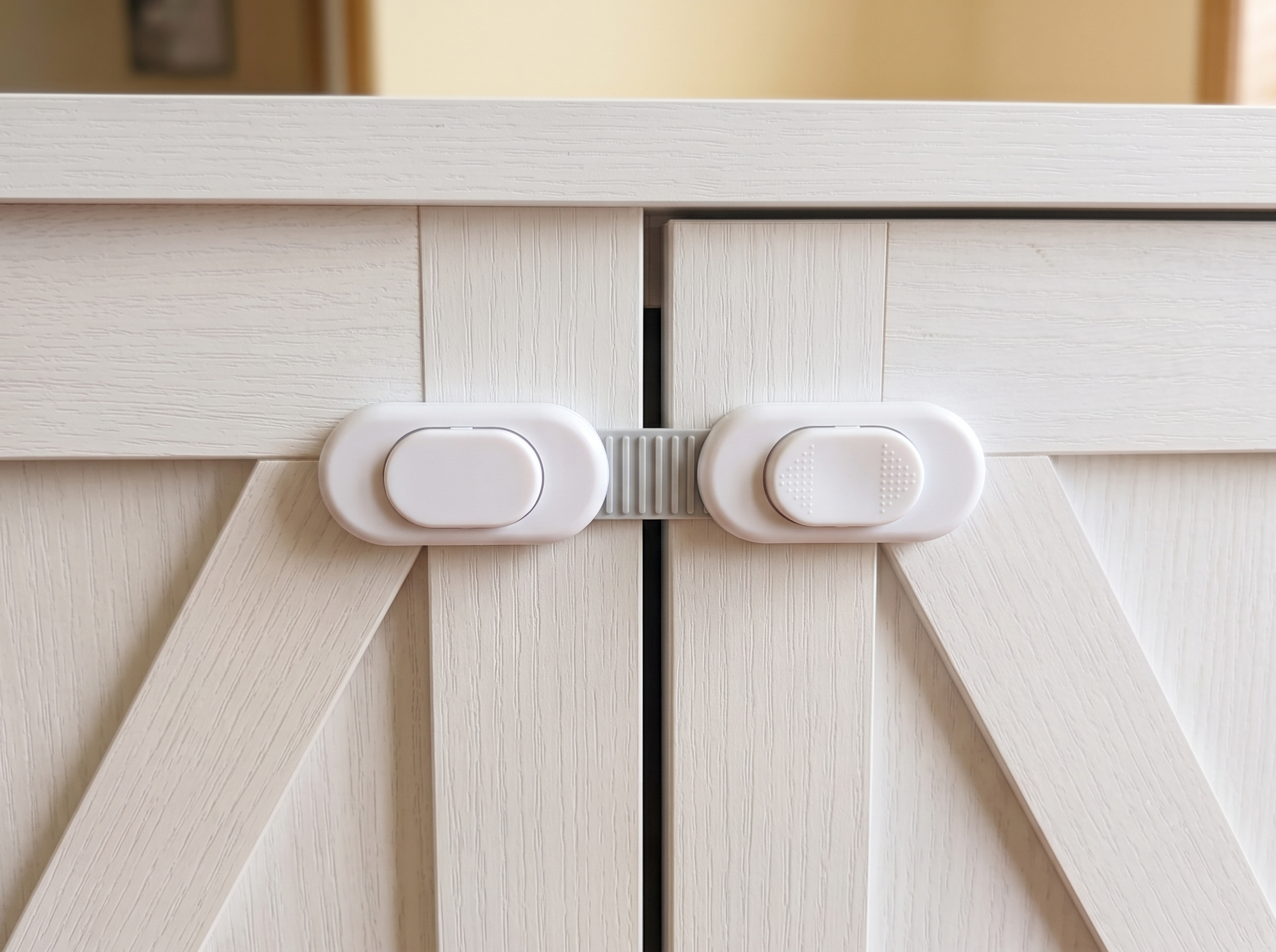 White cabinet safety latch spanning the two barn-door panels of a litter box cabinet to keep them closed