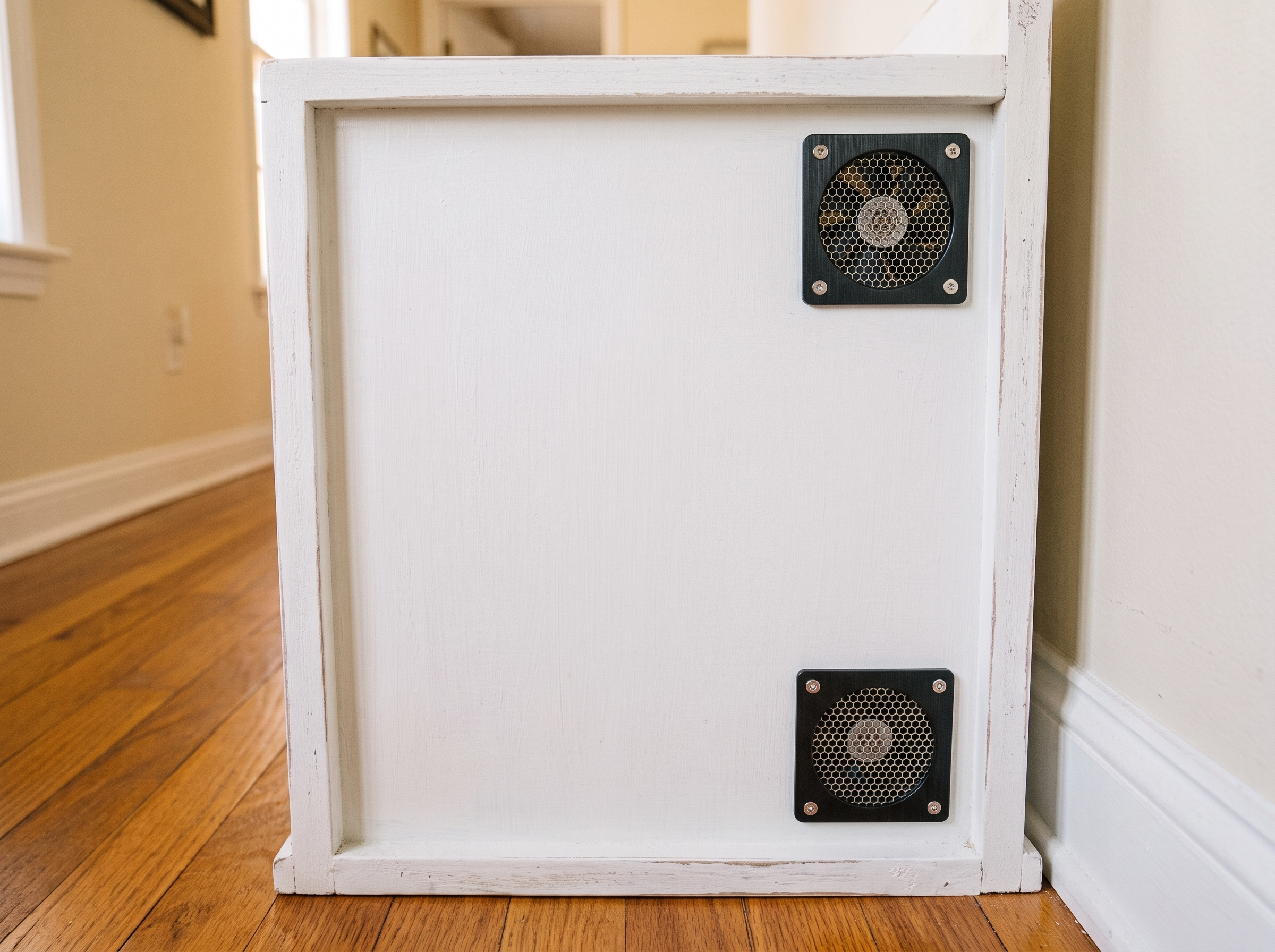 Two small ventilation fans mounted on the exterior back panel of a litter box cabinet for airflow
